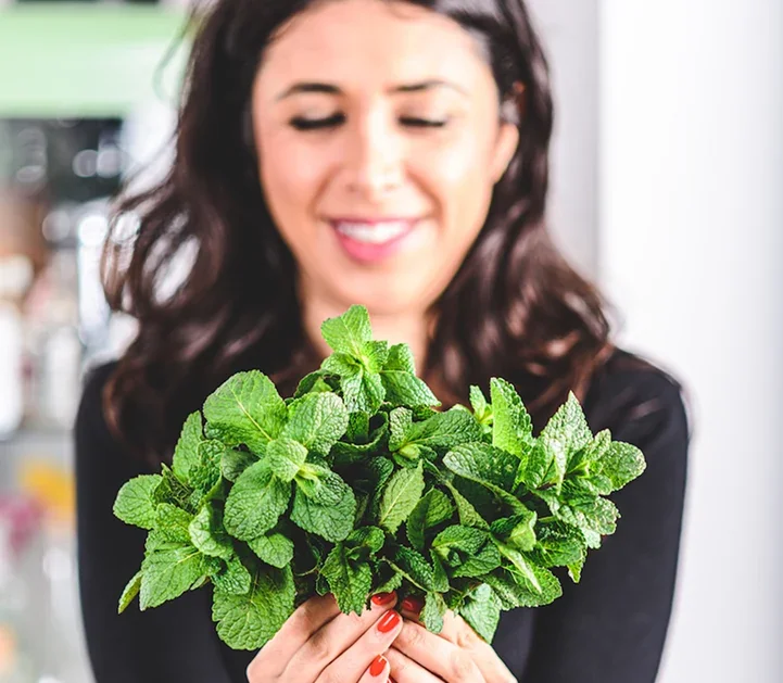 Sherry Adhami, founder of East to West, holding a fresh mint plant