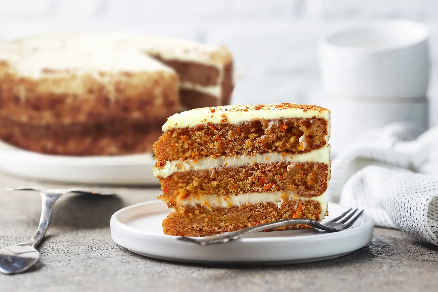 A slice of Rhokett carrot cake with layered icing on a plate