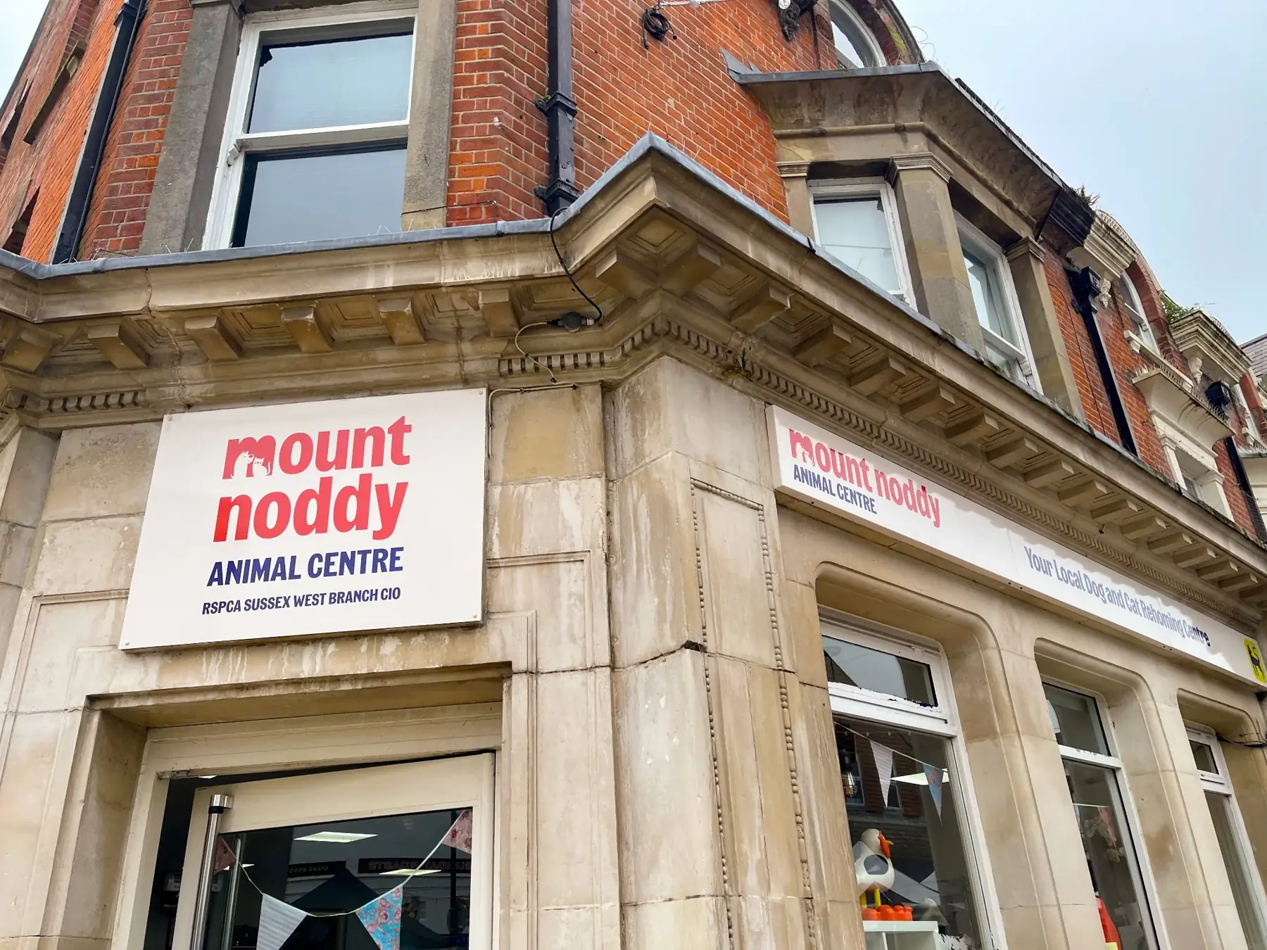 Mount Noddy Animal Centre branded sign on the corner of a charity shop